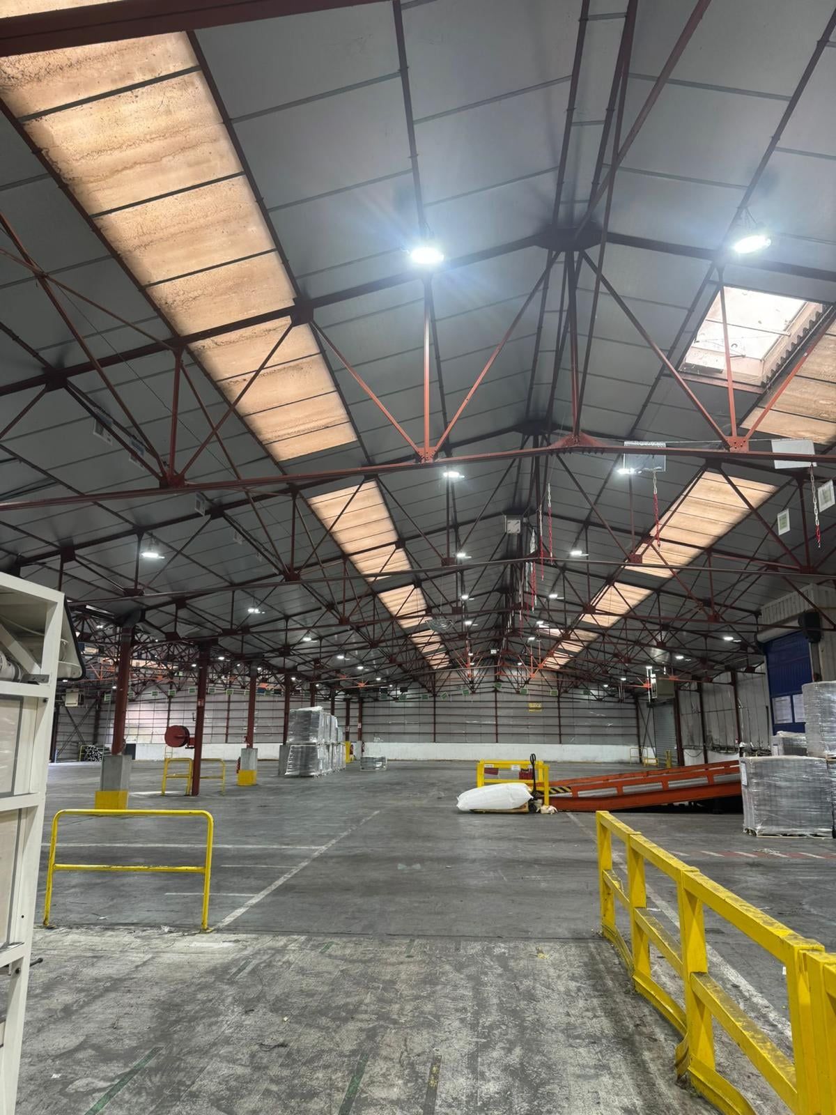 Grand bâtiment à charpente métallique éclairé par des luminaires LED suspendus